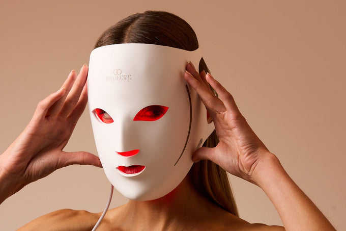 Woman adjusting the LumaLux Face V2 3D LED red light therapy mask with both hands