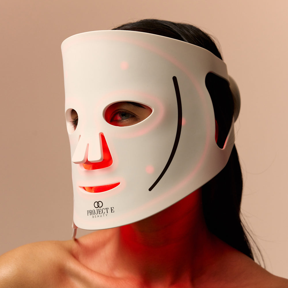 女士戴上 LumaLux Face LED 面罩特写，面罩内侧映出红光